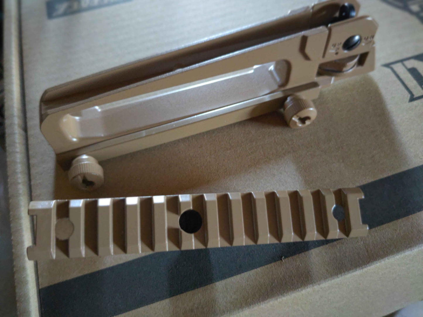 Beige metal tactical m16 carry handle and rail and clip on a cardboard background